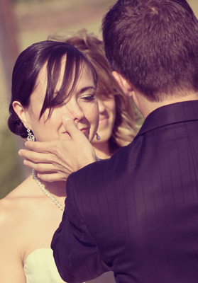 Groom wiping tears from Bride