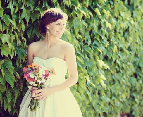 Bride against wall of flowers